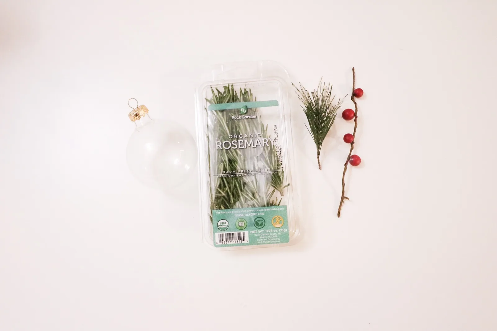 Clear glass ball ornaments filled with sprigs of fresh rosemary and greenery