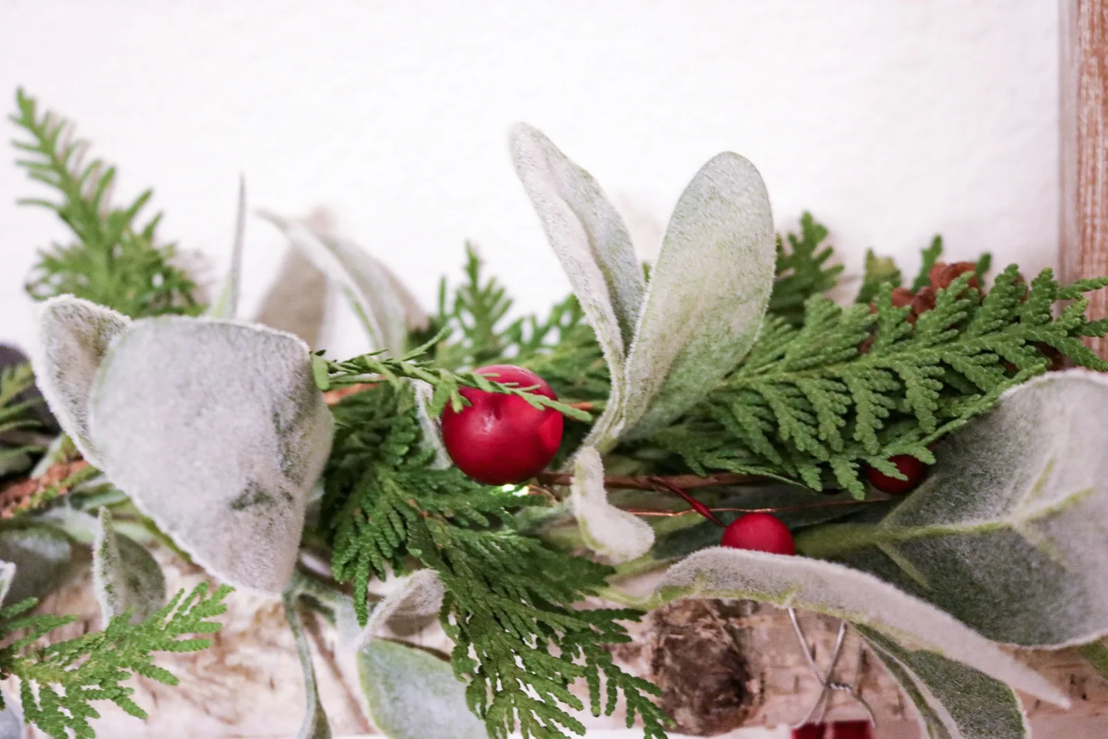 Fresh cedar tucked into a lambs ear garland on a mantel for Christmas